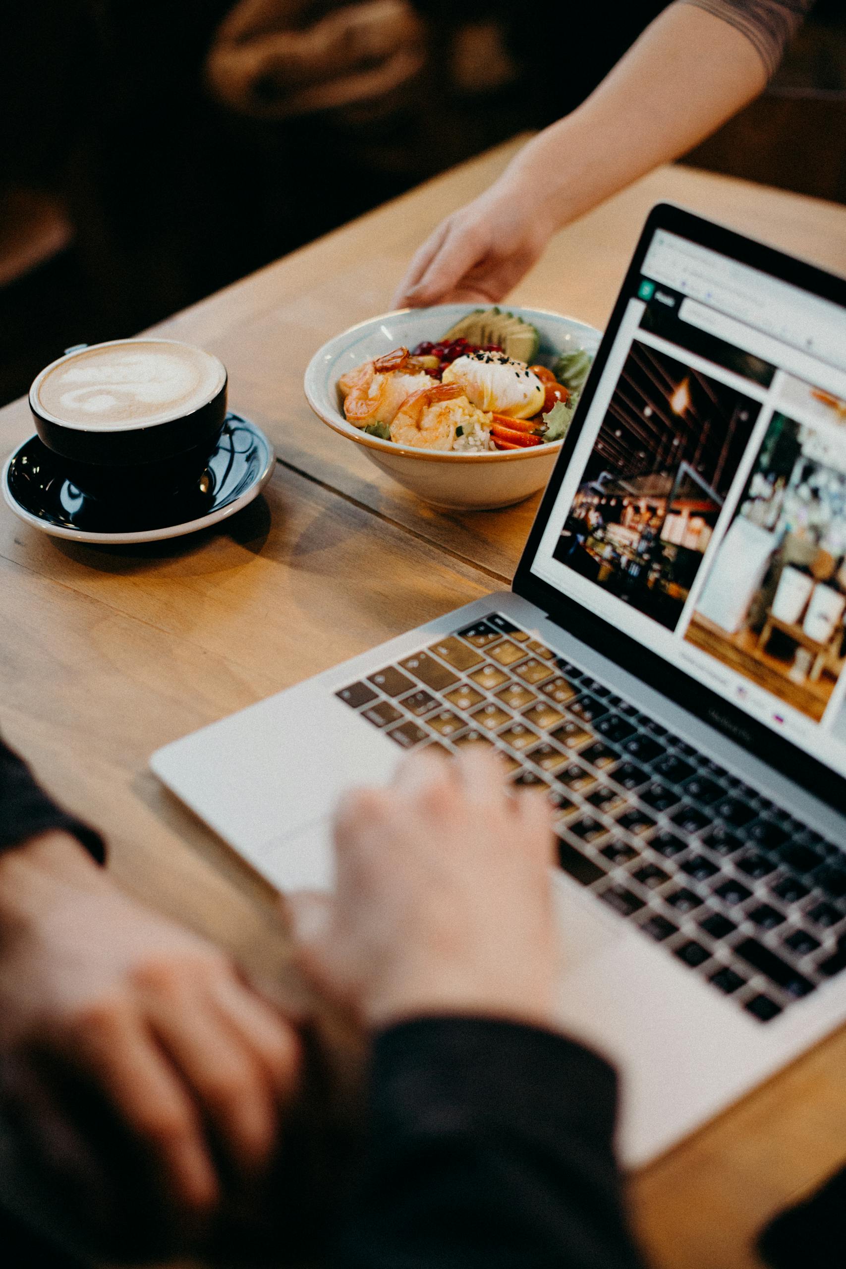A contemporary workspace with a laptop, coffee, and a bowl of soup, ideal for remote work settings.